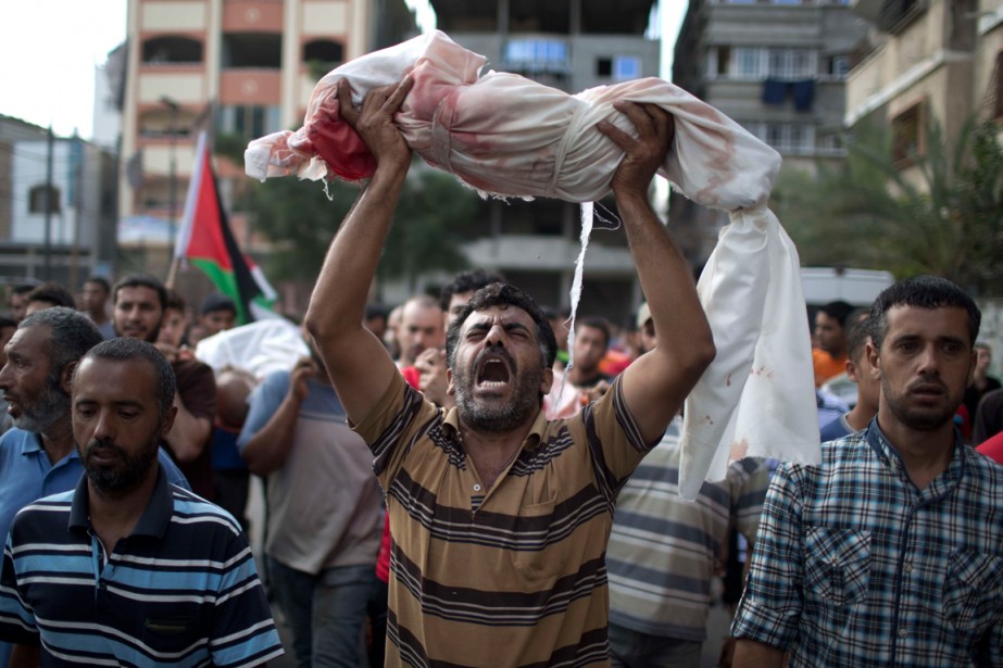 Palestino carrega corpo de crinça morta durante confronto com Exército de israel na faixa de Gaza