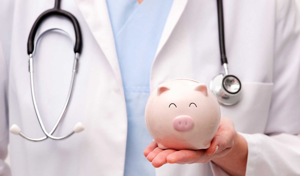 Female doctor with stethoscope holding piggy bank