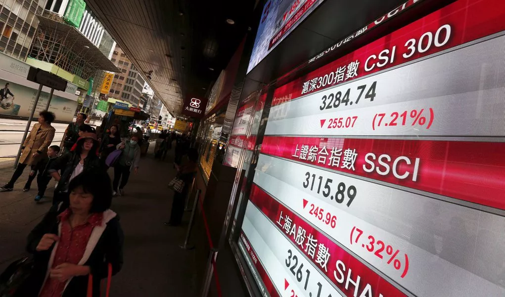 Pessoas passam por painel exibindo cotações de ações de bolsa na China, em Hong Kong
