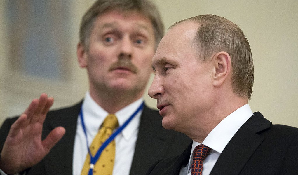 In this photo taken on Thursday, Feb.  12, 2015, Russian President Vladimir Putin,  right, speaks to a journalist as his press secretory  Dmitry Peskov tries to stop questions after the peace talks in Minsk, Belarus, Thursday, Feb. 12, 2015.  Peskov told 