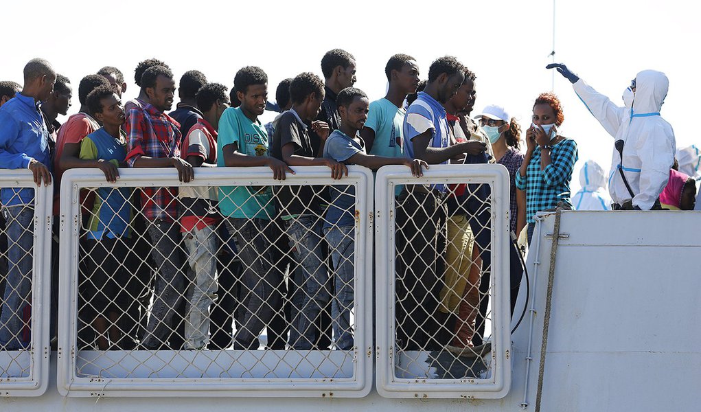 Imigrantes aguardam para desembarcar de um navio italiano em Augusta, na ItÃ¡lia, no domingo. 23/08/2015 REUTERS/Antonio Parrinello