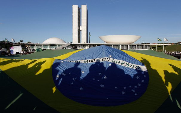 Demonstrators open a Brazil's flag in front of the National Congress during a protest in Brasilia, Brazil, Wednesday, June 26, 2013. The wave of protests that hit Brazil on June 17 began as opposition to transportation fare hikes, then expanded to a list 