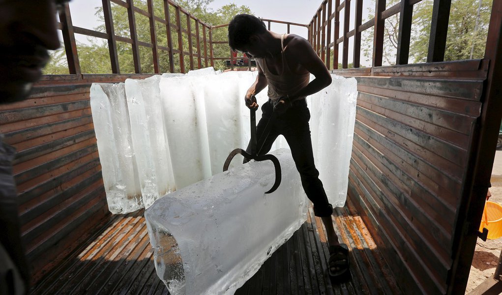 Trabalhador corta gelo para resfriamento de alimentos em mercado na Ãndia.   19/05/2015  REUTERS/Amit Dave