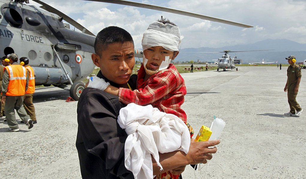Homem segura uma crianÃ§a, ferida no terremoto de sÃ¡bado, depois que soldados indianos os levaram de Trishuli Bazar ao aeroporto em Katmandu, no Nepal, nesta segunda-feira. 27/04/2015 REUTERS/Jitendra Prakash