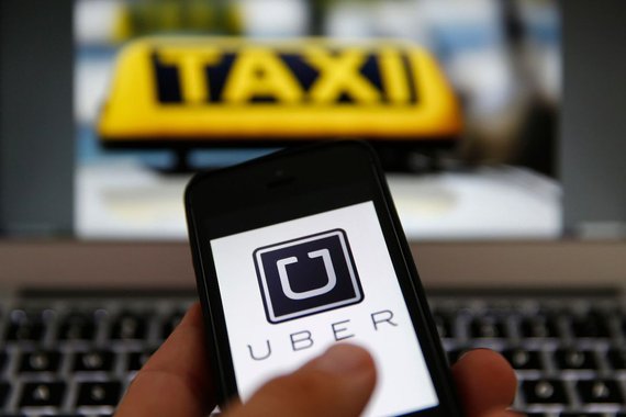 An illustration picture shows the logo of car-sharing service app Uber on a smartphone next to the picture of an official German taxi sign in Frankfurt, September 15, 2014. A Frankfurt high court will hold a hearing on a recent lawsuit brought against Ube