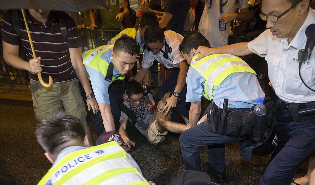 Policiais tentam retirar manifestante de rua ocupada em protesto em Hong Kong.  REUTERS/Tyrone Siu