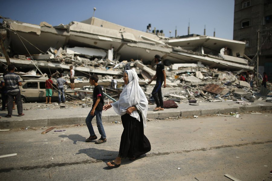 Palestinos caminham próximos aos escombros de um prédio residencial que a polícia diz ter sido destruído em um ataque aéreo de Israel, em Gaza. 22/07/2014.
 REUTERS/Mohammed Salem