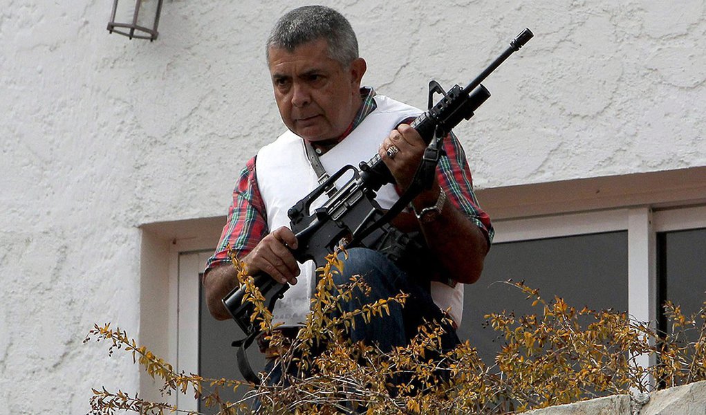 Angel Vivas, a retired army general and anti-Maduro protester, stands in his house with an automatic weapon as he resists be detained in Caracas February 23, 2014. According to local media, President Nicolas Maduro ordered the detention of Vivas on Saturd