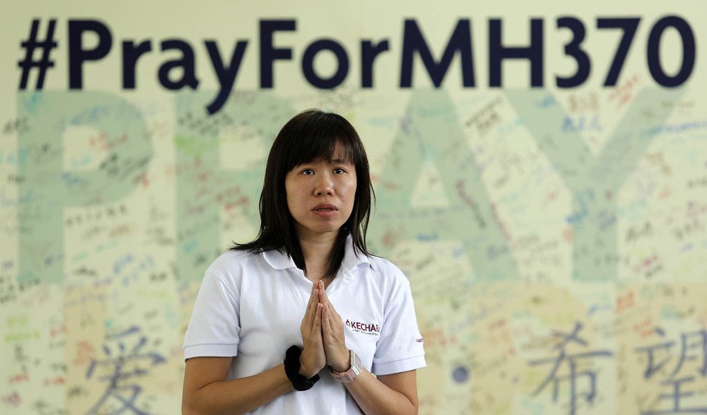 A woman prays for passengers onboard the missing Malaysia Airlines flight MH370 at Kechara retreat centre in Bentong outside Kuala Lumpur April 13, 2014. The search for the missing jetliner resumed on Saturday, five weeks after the plane disappeared from 