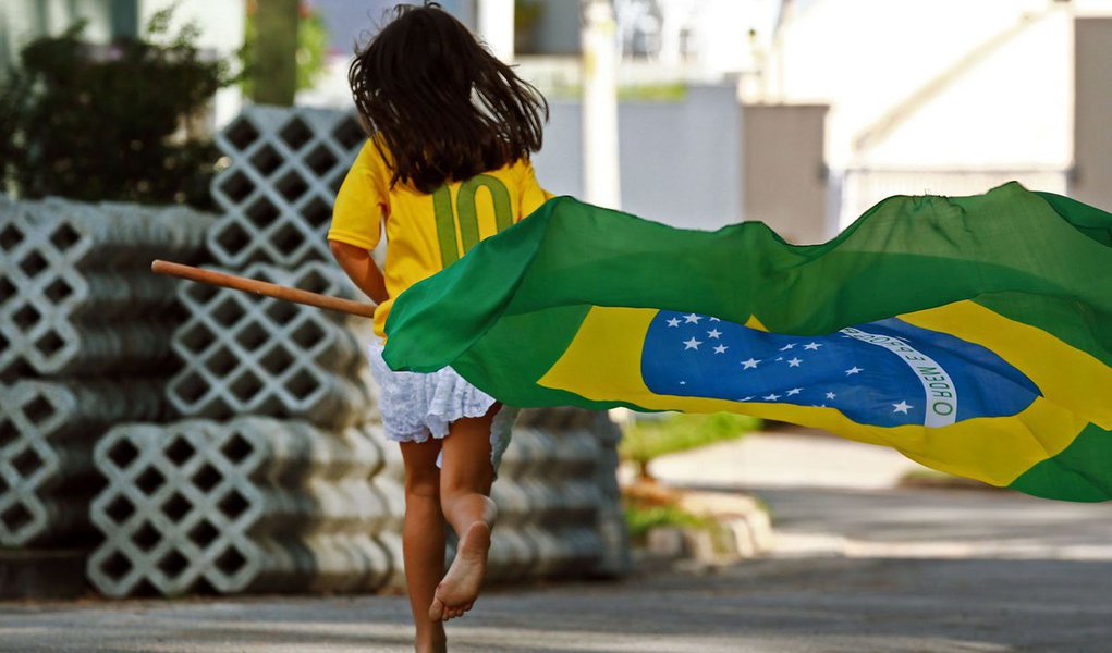 SÃO PAULO (SP) - BRASIL - 12-06-2014 - COPA DO MUNDO 2014 - Perto do momento da Abertura da Copa do Mundo 2014, menina corre com a bandeira do Brasil em rua de Osasco, Grande São Paulo.- (Foto: Chico Cardillo/FOTOS PÚBLICAS)