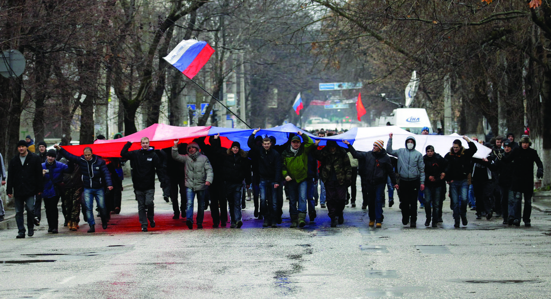 Pro-Russian demonstrators march with a huge Russian flag during a protest in front of a local government building in Simferopol, Crimea, Ukraine, Thursday, Feb. 27, 2014. Ukraine's acting interior minister says Interior Ministry troops and police have bee