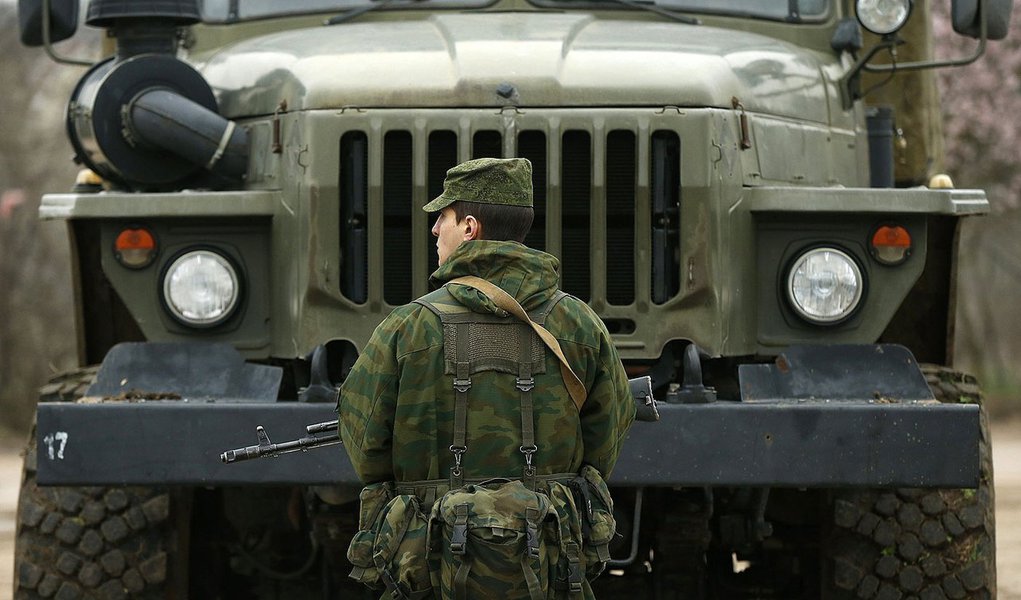 A uniformed man, believed to be a Russian serviceman, stands guard near a Ukrainian military base outside the city of Sevastopol, March 7, 2014. President Vladimir Putin rebuffed a warning from U.S. President Barack Obama over Moscow's military interventi