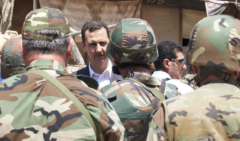 Syria's President Bashar al-Assad (C) chats with military personnel during his visit to a military site in the town of Daraya, southwest of Damascus, on the 68th anniversary of army day, in this handout photograph distributed by Syria's national news agen