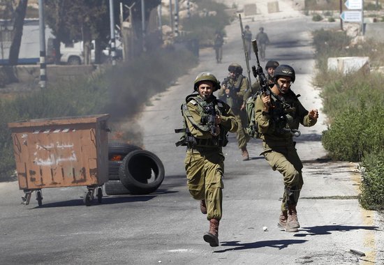 Soldados israelenses correm durante confrontos com manifestantes palestinos, perto de Ramallah, que protestavam contra a ofensiva de Israel em Gaza.  25/7/2014.  REUTERS/Mohamad Torokman