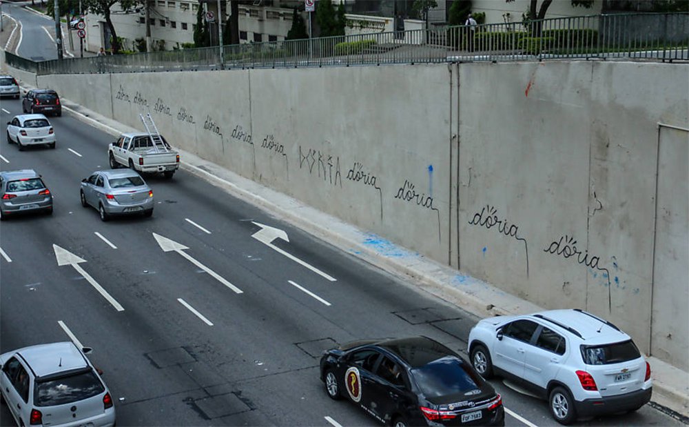 Após o prefeito de São Paulo, João Doria (PSDB), mandar cobrir de tinta cinza os muros da Avenida 23 de Maio, que estavam cheios de grafites, seu nome foi pichado repetidas vezes; funcionários da Prefeitura já pintaram novamente o muro, apagando as pichações