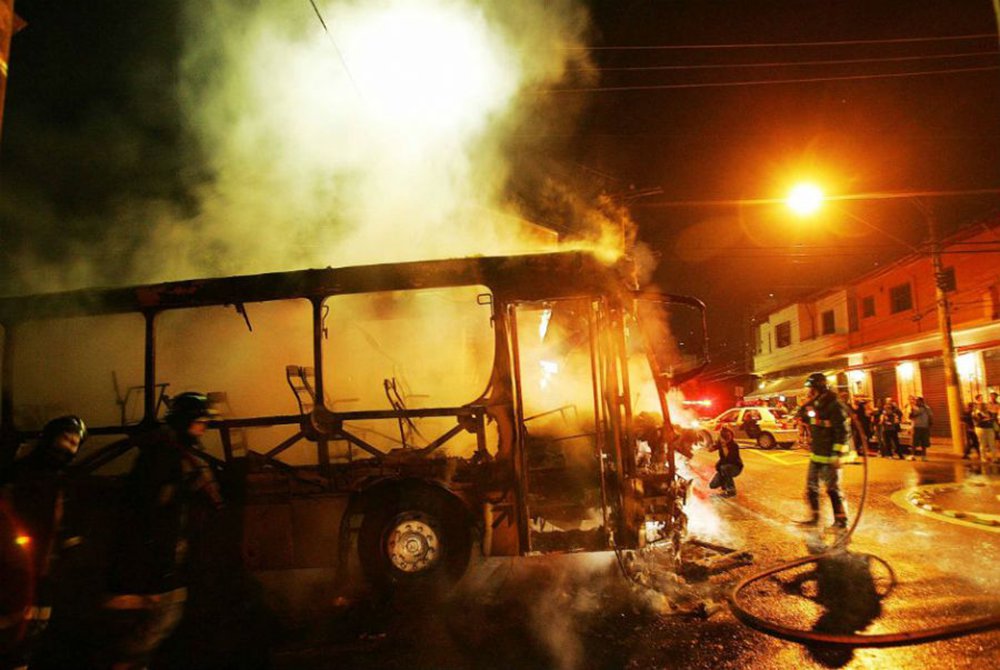 Homens do Corpo de Bombeiros tentam conter fogo em um ônibus