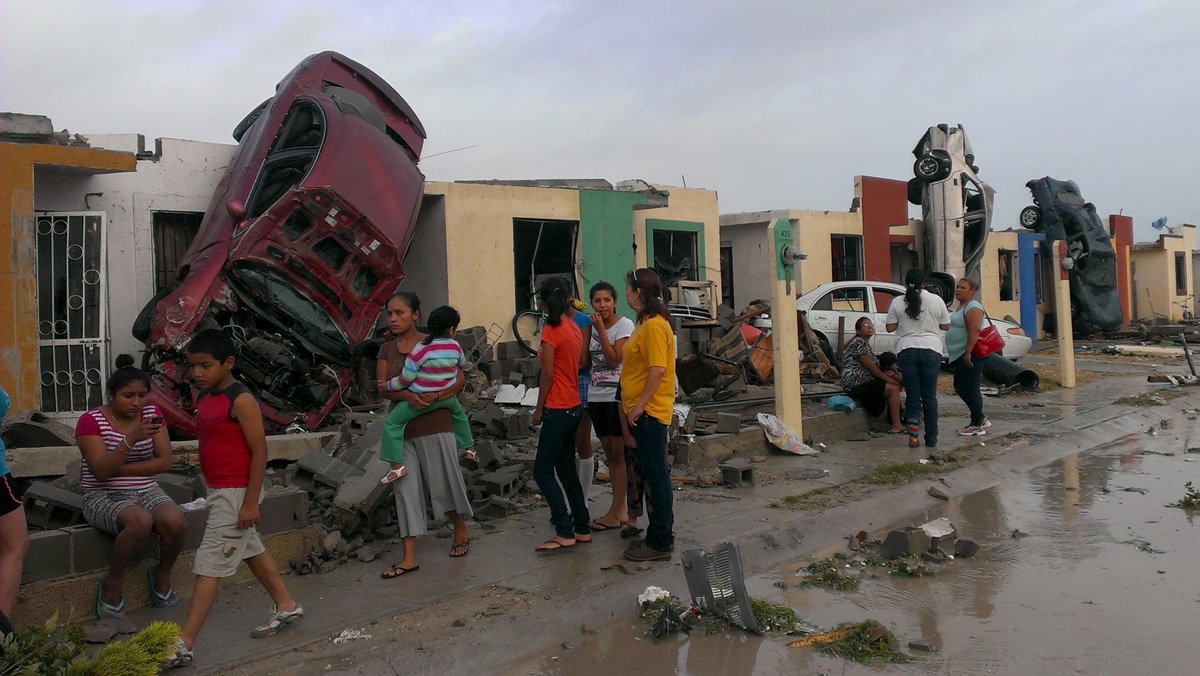 Moradores saem Ã  rua, enquanto carros arrastados por um tornado sÃ£o vistos numa rua em Ciudad Acuna, no MÃ©xico, nesta segunda-feira. 25/05/2015 REUTERS/Ramiro Gomez