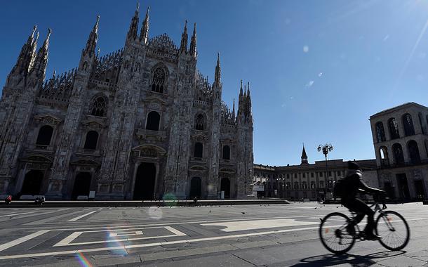 Ciclista passa em frente à catedral de Milão, com ambientes públicos desertos por conta do coronavírus