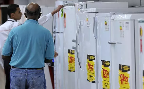 Vendedor mostra a cliente geladeiras da linha branca