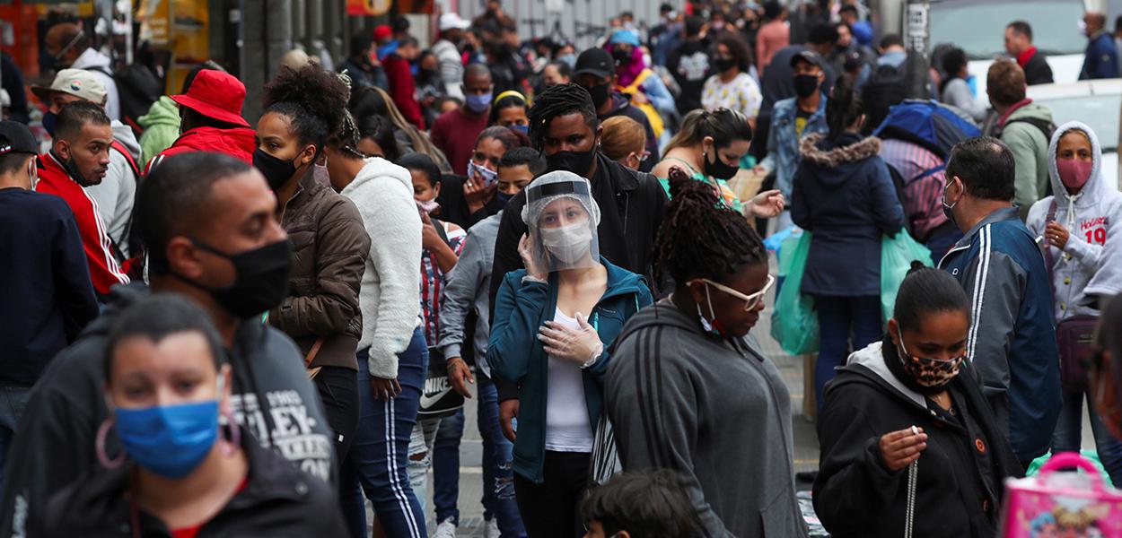 Pessoas caminham em rua de comércio popular em São Paulo