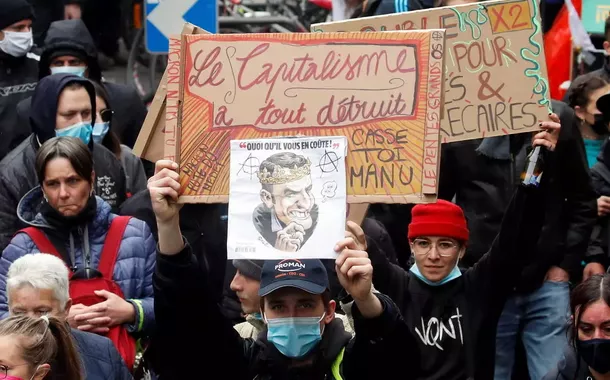 Um manifestante segura um cartaz com dizeres "O capitalismo destruiu tudo"