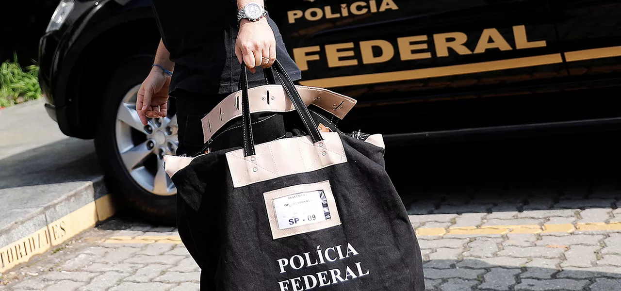 Policial federal carrega uma bolsa ao chegar à sede da Polícia Federal em São Paulo