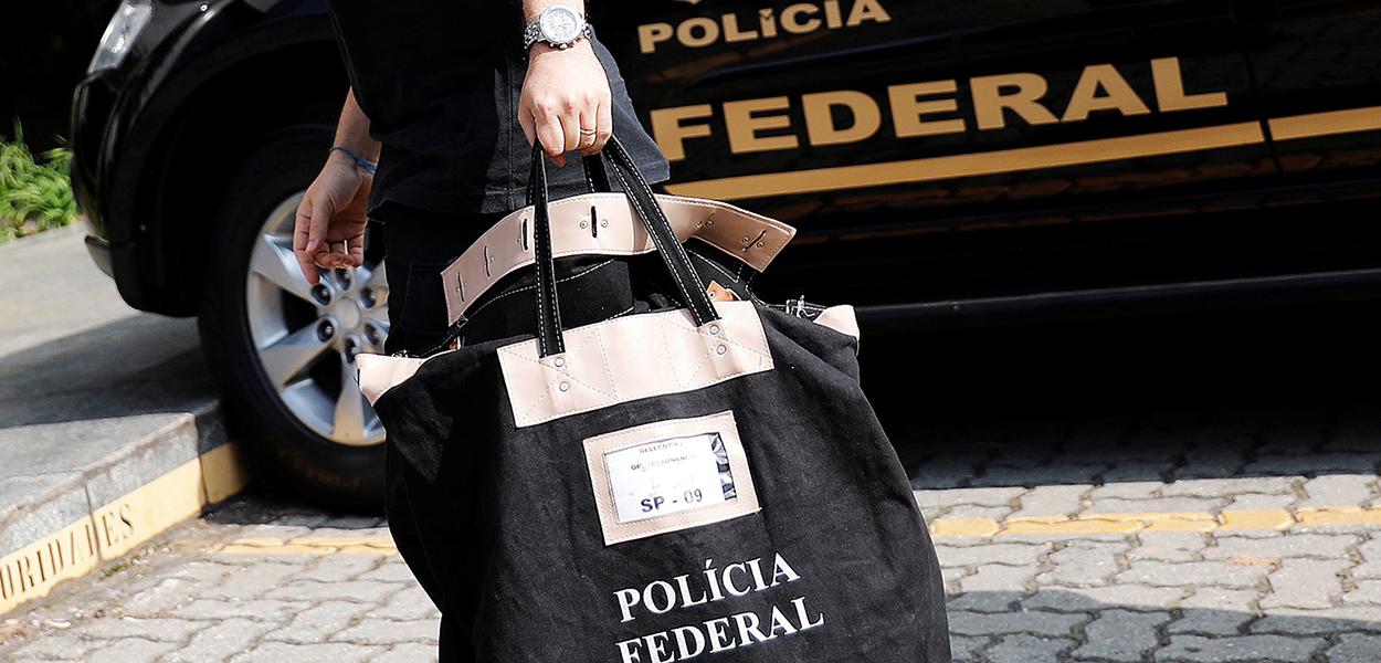 Policial federal carrega uma bolsa ao chegar à sede da Polícia Federal em São Paulo