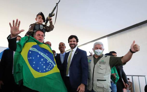 Bolsonaro se enrola na bandeira nacional para foto com criança segurando arma de brinquedo