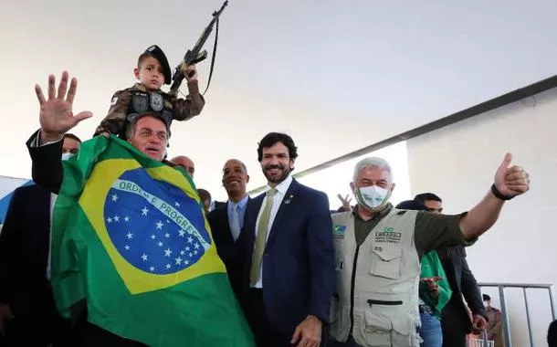 Bolsonaro se enrola na bandeira nacional para foto com criança segurando arma de brinquedo