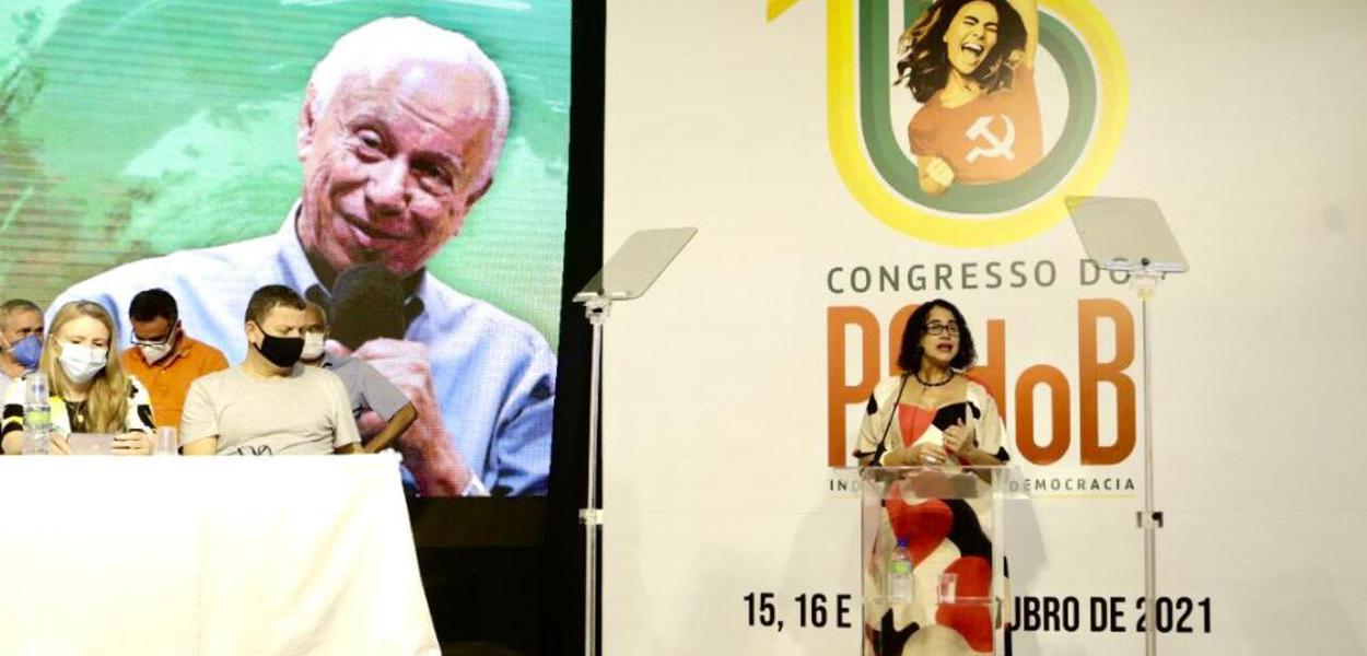Luciana Santos, presidente do PCdoB fala no 15º Congresso. No painel, ao fundo, imagem de Haroldo Lima, dirigente do partido falecido em março último, homenageado no encontro