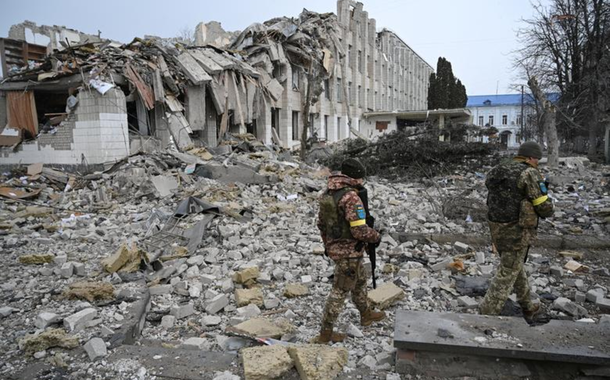 Militares ucranianos caminham perto de um prédio escolar destruído por um bombardeio em Zhytomyr, Ucrânia, em 4 de março de 2022