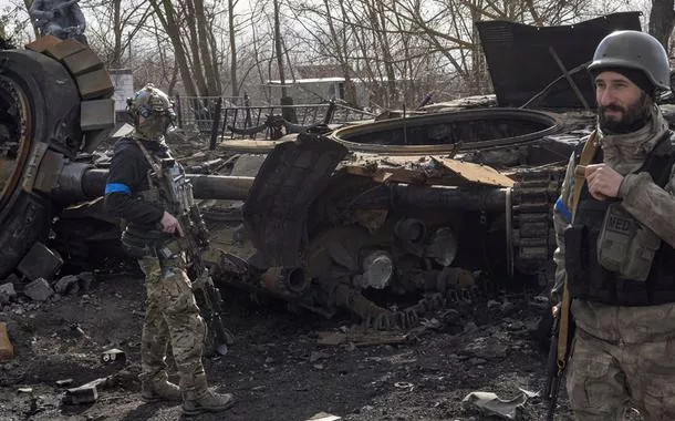 Soldados ucranianos passam por destroços de tanque russo destruído