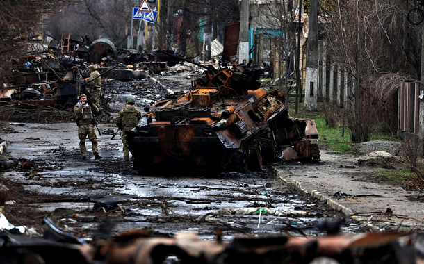 Um soldado tira uma foto de seu companheiro enquanto ele posa ao lado de um tanque russo destruído e veículos blindados, em meio à invasão da Rússia na Ucrânia em Bucha, na região de Kiev, Ucrânia 2 de abril de 2022