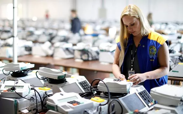 Funcionária da Justiça Eleitoral com urnas eletrônicas