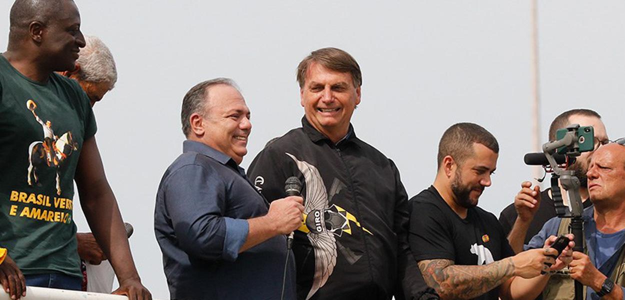 Eduardo Pazuello (com microfone na mão) e Jair Bolsonaro (agasalho preto)