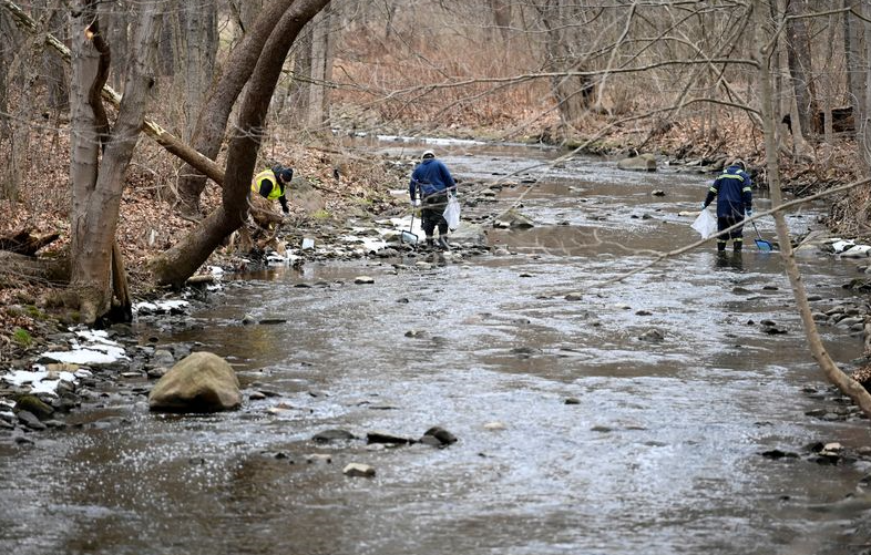 Agentes ambientais removem peixes mortos pela contaminação em um rio próximo ao local de descarrilamento de trem na Palestina Oriental, Ohio, EUA, 6 de fevereiro de 2023