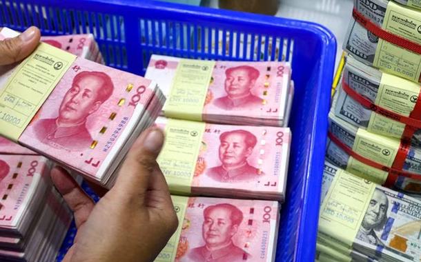 Funcionário de banco conta renminbi da China (RMB) ou notas de yuan ao lado de notas de dólar americano em um Kasikornbank em Bangkok, Tailândia - 26.01.2023