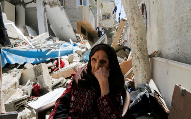 A palestina Intisar Muhana, 97, que foi forçada a fugir da vila de al-Masmiyya durante a 'Nakba' na guerra em torno da independência de Israel em 1948 e cuja casa foi destruída em um ataque israelense em Gaza, senta-se em frente aos escombros de sua casa, na cidade de Gaza, 14 de maio de 2023