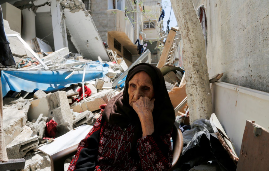 A palestina Intisar Muhana, 97, que foi forçada a fugir da vila de al-Masmiyya durante a 'Nakba' na guerra em torno da independência de Israel em 1948 e cuja casa foi destruída em um ataque israelense em Gaza, senta-se em frente aos escombros de sua casa, na cidade de Gaza, 14 de maio de 2023