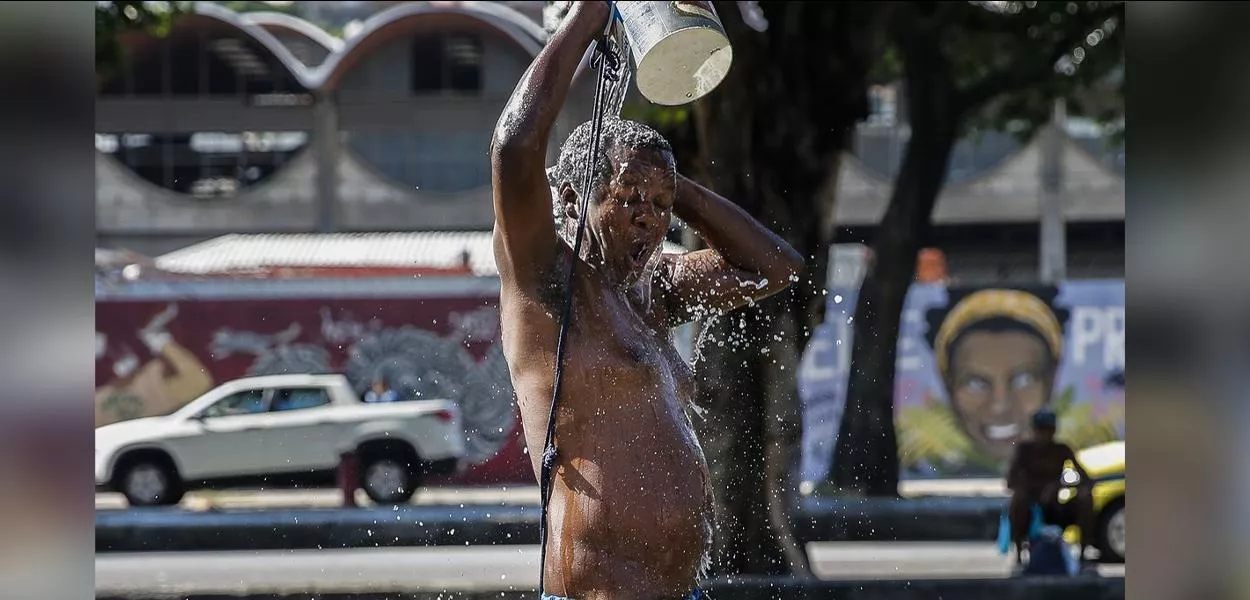 Homem toma banho na rua em meio ao calor no Rio de Janeiro 
