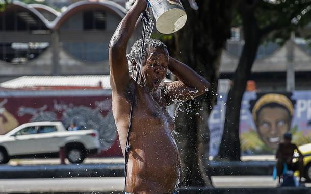 Homem toma banho na rua em meio ao calor no Rio de Janeiro 