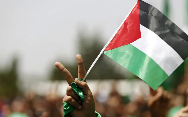 Um estudante que apoia o Hamas segura uma bandeira palestina em um comício na Universidade Birzeit, na cidade de Ramallah, na Cisjordânia