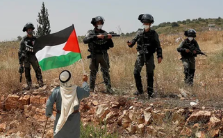 Um palestino protesta em frente a soldados israelenses