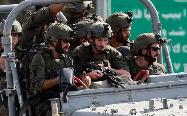 Militares israelenses avançam em uma estrada no sul de Israel, enquanto foguetes são lançados da Faixa de Gaza, nos arredores de Sderot, em 7 de outubro de 2023. 