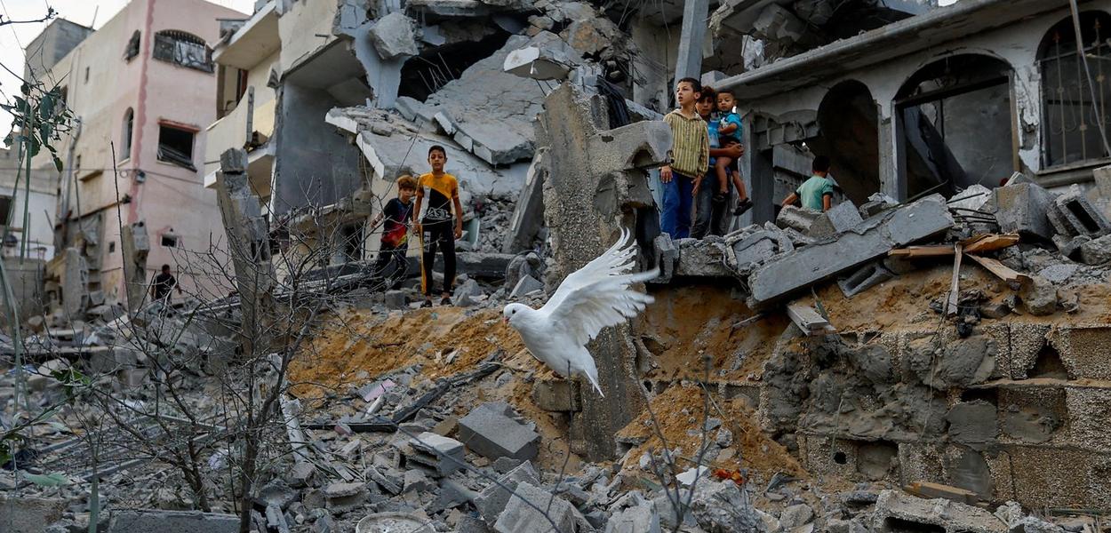 Pomba voa sobre os destroços de casas destruídas por ataques israelenses, em Khan Younis, no sul da Faixa de Gaza
