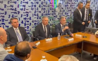 Embaixadorjoga bet apkIsrael, sentado, entre Jair Bolsonaro e outra pessoa com a mão levantada,joga bet apkevento com parlamentares da extrema direita na Câmara