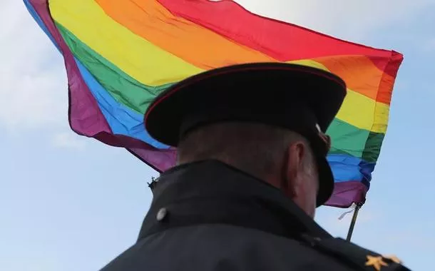 Membro das forças de segurança da Rússia e bandeira LGBTQIAPN+