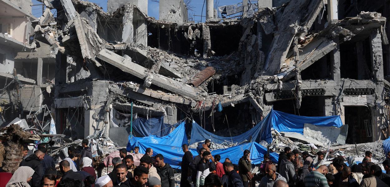 Palestinos perto das ruínas de casas e edifícios destruídos pelos ataques israelenses