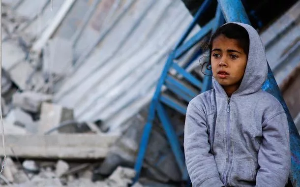 Criança palestina sentada no local de um ataque israelense a uma casa em Rafah, no sul da Faixa de Gaza