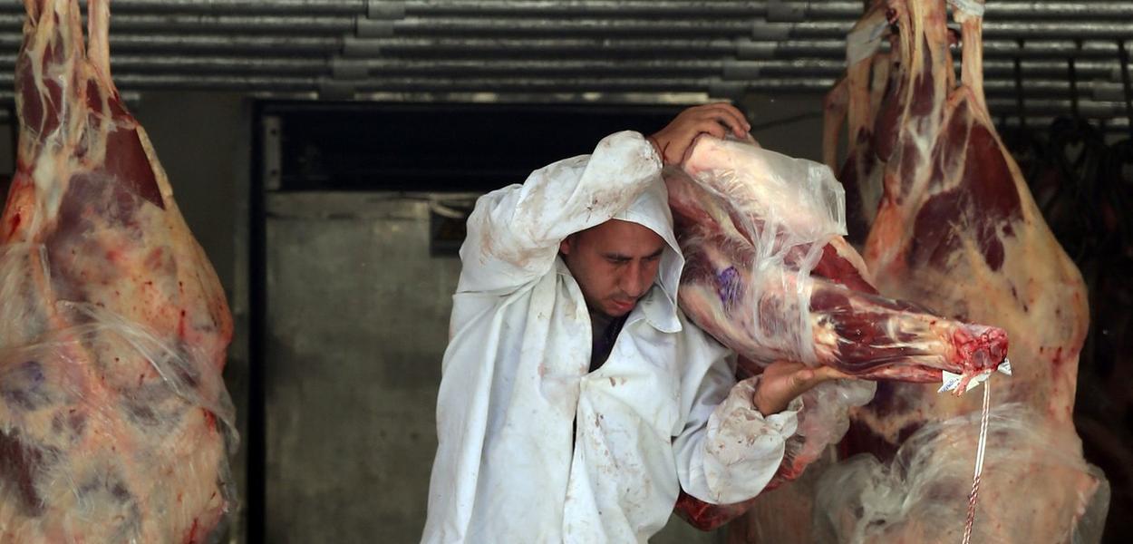 Açougueiro descarrega carne de um caminhão do lado de fora de um açougue em São Paulo